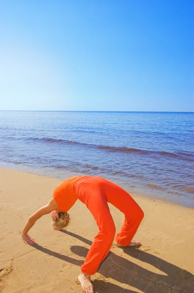 금발 소녀는 해변에 일부 요가 이동 보여줍니다. — 스톡 사진