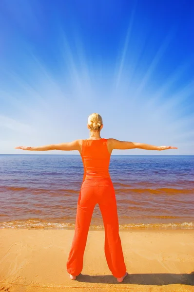 Blond flicka mediterar på stranden — Stockfoto