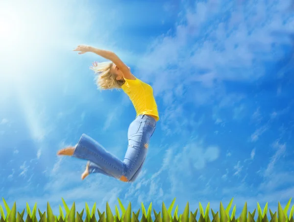 Prachtige blond meisje springt over groen gras — Stockfoto
