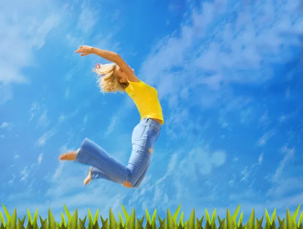 Vacker blond flicka hoppar över grönt gräs — Stockfoto