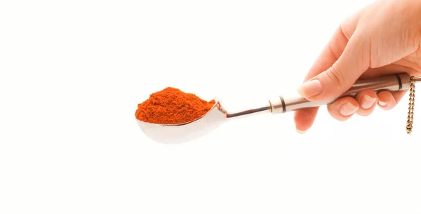 Hand holding a silver spoon with a spice — Stock Photo, Image