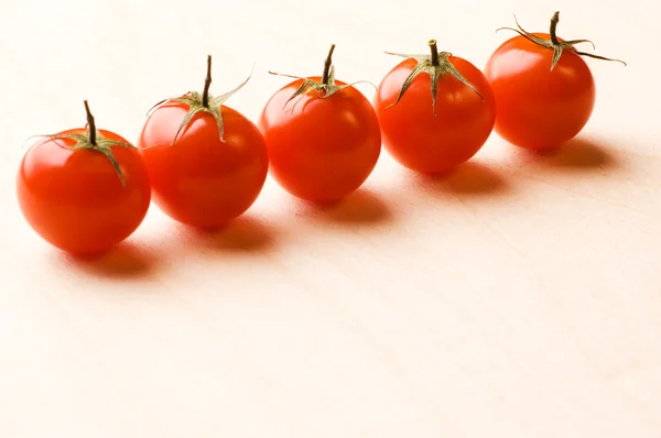Line of tomatoes on wooden plate — Stock Photo, Image
