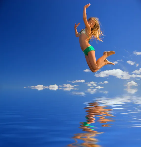 Маленькая девочка прыгает через воду Стоковое Изображение