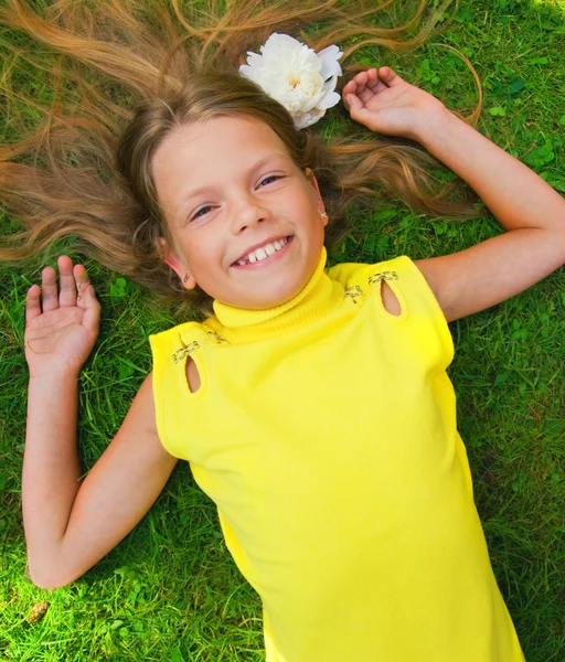 Chica joven feliz acostado en una hierba verde Imagen de stock