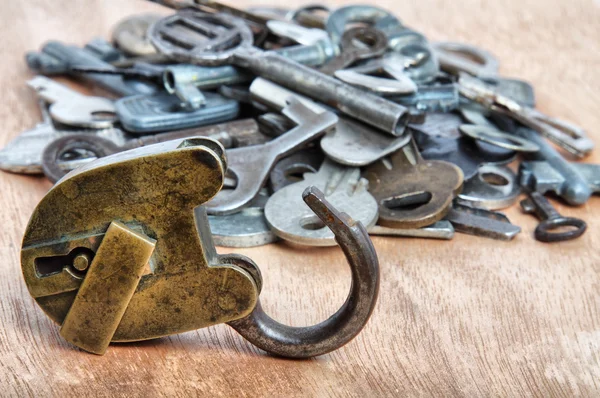 Antiguo candado y montones de llaves en madera — Foto de Stock