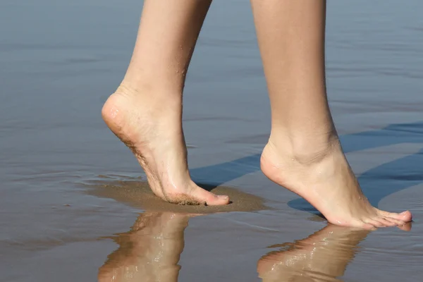 Beautiful female feet on sea sand — Stok fotoğraf