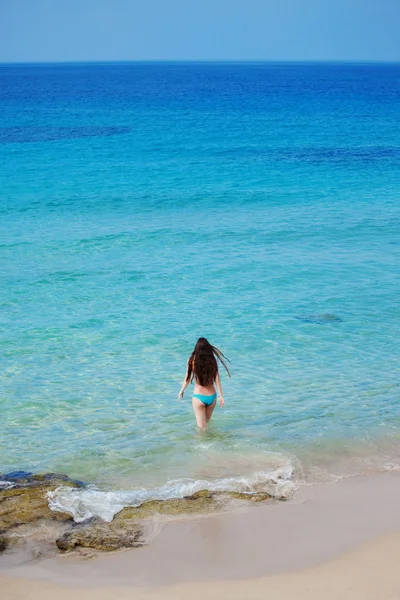 The beautiful girl in blue bikini costs in transparent sea water — Stock Photo, Image