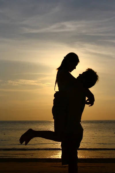 Ευτυχισμένο ζευγάρι στο ηλιοβασίλεμα παραλία - silhouett Εικόνα Αρχείου