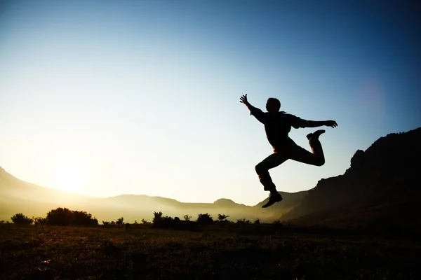 Силуэт молодого мужчины, прыгающего через фон заката с копирайтом — стоковое фото
