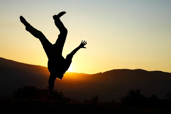 Homem feliz nas montanhas ficar cabeça sobre saltos em uma mão Fotografia De Stock