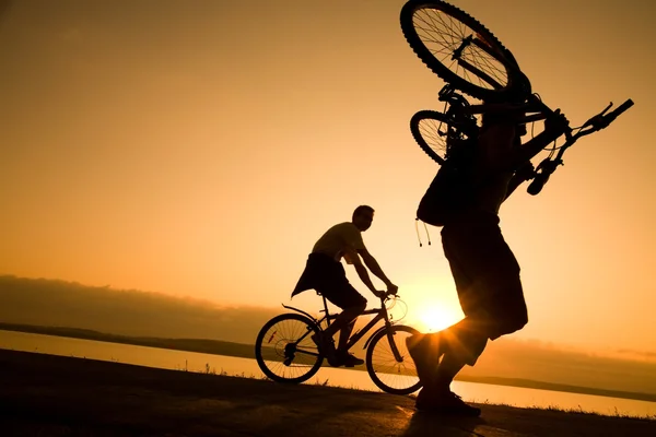 Чоловік несе велосипед на заході сонця — стокове фото