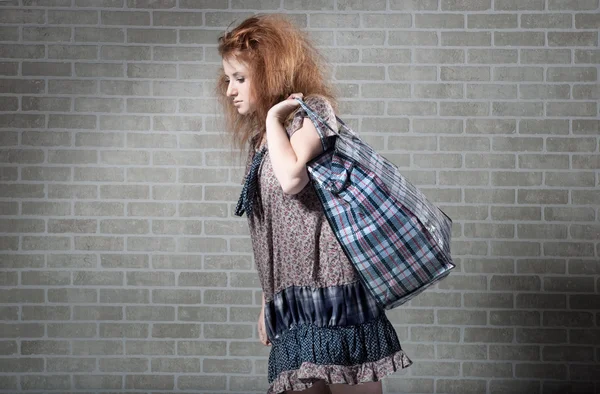 Втомлена руда жінка з сумкою для покупок . — стокове фото
