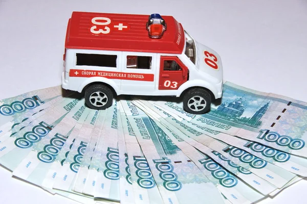 Carro de brinquedo ambulância e dinheiro — Fotografia de Stock