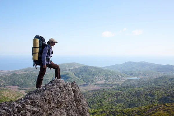 Девочка с рюкзаком, стоящая на высокой скале — стоковое фото
