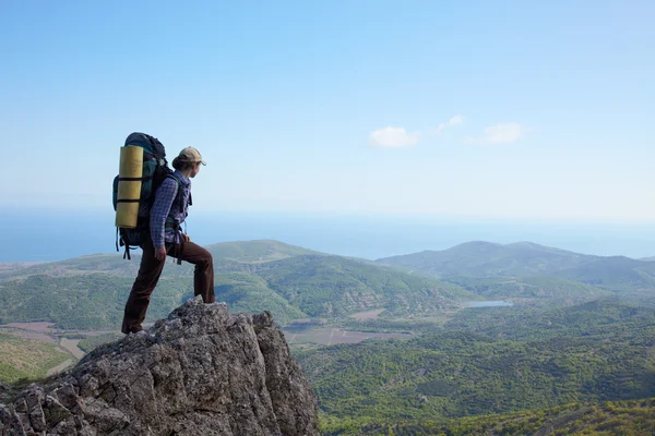 Backpacker menina de pé em uma rocha alta — Fotografia de Stock