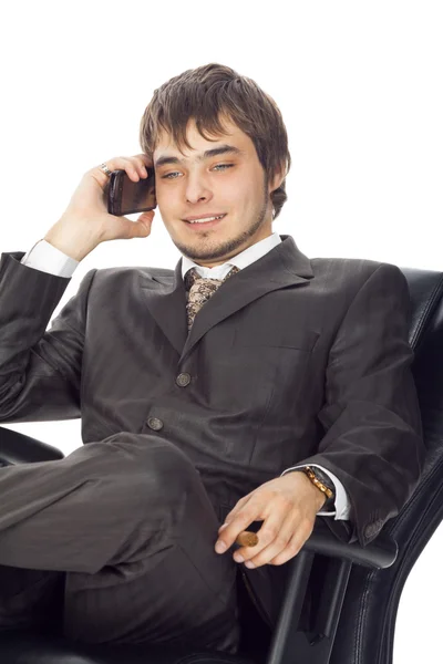 Ung affärsman sitter i en fåtölj och leende talar o — Stockfoto
