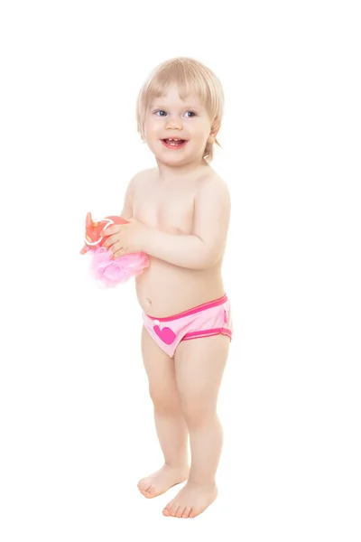 Sorrindo bebê menina de pé e segurando uma esponja para tomar banho — Fotografia de Stock