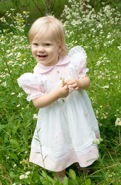 Jonge mooie babymeisje legt op een gras — Stockfoto