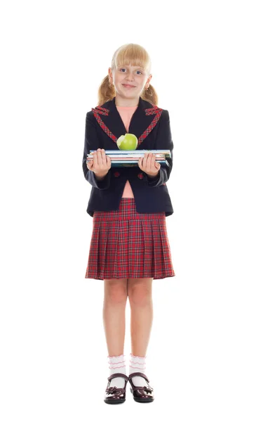 Chica en uniforme escolar sosteniendo una pila de libros y morder la manzana —  Fotos de Stock