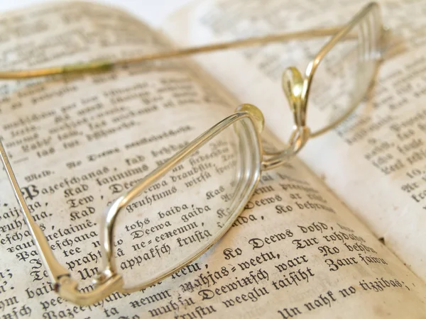 Livro aberto com óculos de cor dourada — Fotografia de Stock