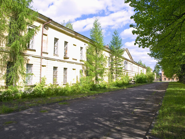 Long low-rise building with the road and trees at the sunny day