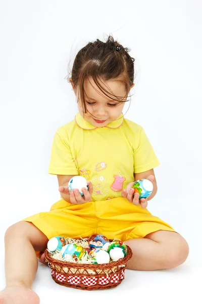 Süßes kleines Mädchen lächelt und hält bunte Ostereier — Stockfoto