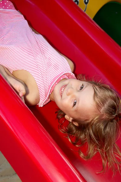 Menina cavalgando em um balanço no playground — Fotografia de Stock