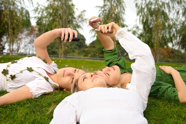 Девушки разговаривают по мобильному в парке — стоковое фото