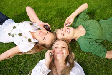 Girls talking on mobile in the park clipart