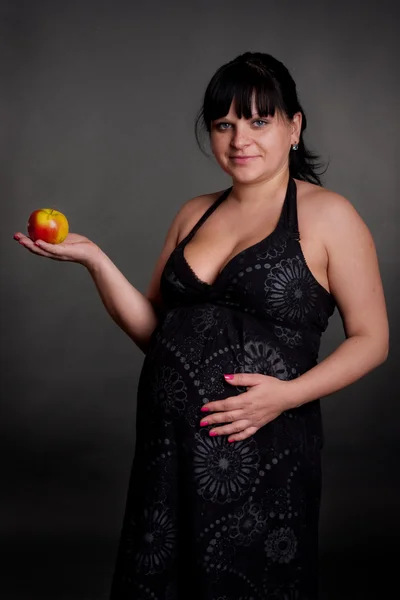 Беременная женщина с красным яблоком — стоковое фото