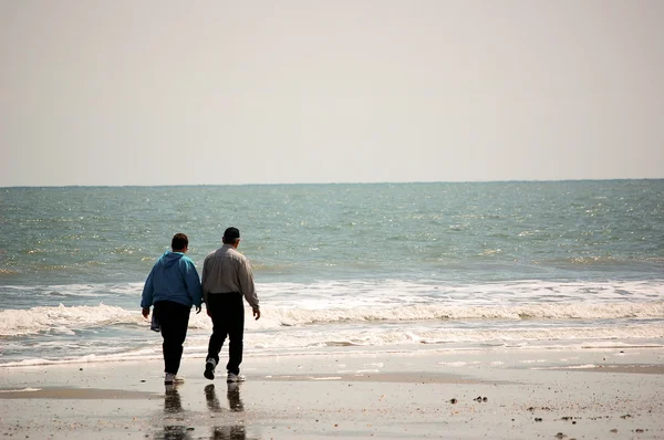 Ouder koppel wandelen op het strand — Stockfoto