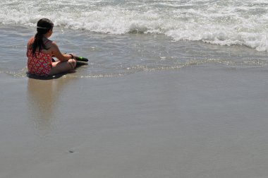 küçük kız okyanusta sörf için bekler.