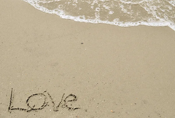 Amor escrito en la arena con olas — Foto de Stock