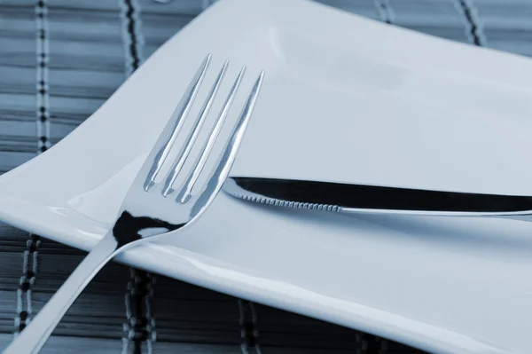 Fork and a knife laying on a plate — Stock Photo, Image