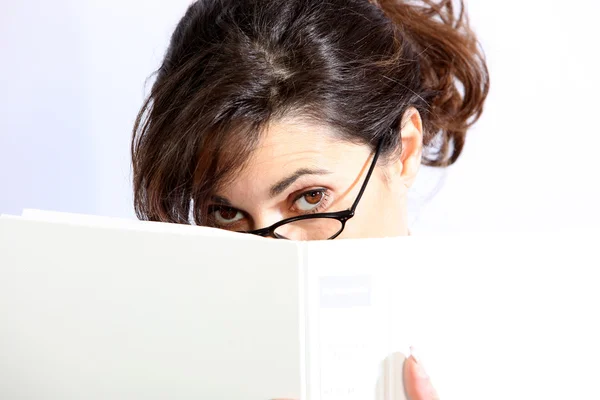 En ung kvinna gömmer sig bakom en mapp — Stockfoto