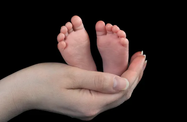 Baby fötter i mödrar hand Stockbild