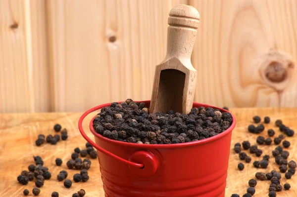 Pimenta preta milho em um balde vermelho — Fotografia de Stock