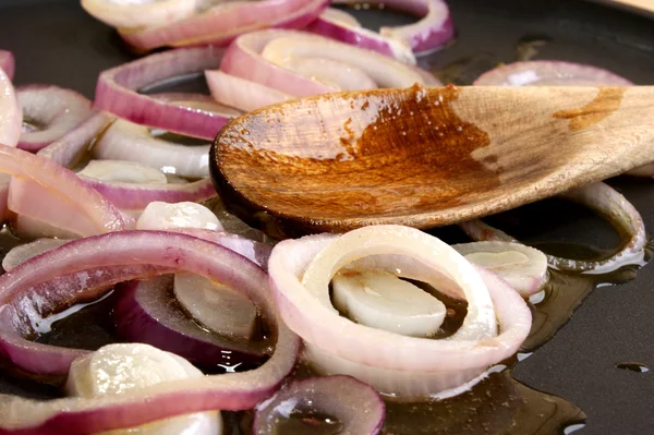 Algunos aros de cebolla con mantequilla en una sartén — Foto de Stock