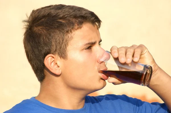 Um adolescente masculino está bebendo uma coca de vidro — Fotografia de Stock