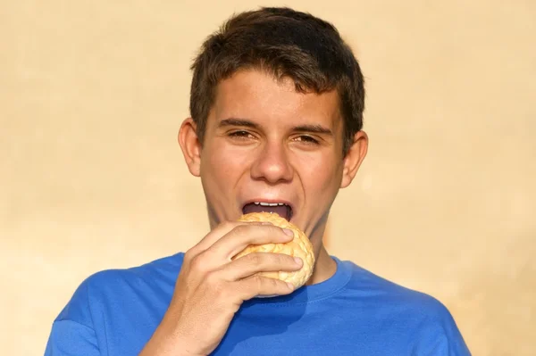Manlig tonåring äta ett bröd rulle — Stockfoto