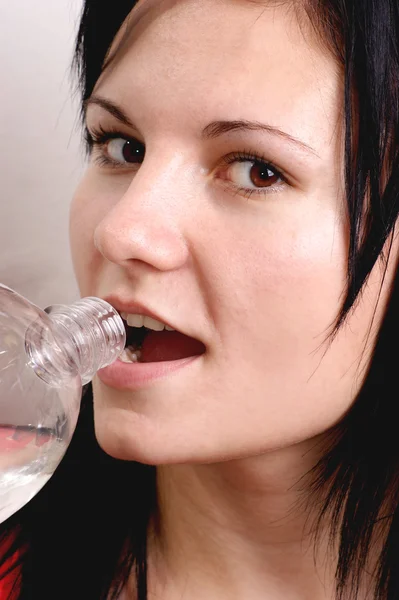 Uma jovem bebe água de uma garrafa — Fotografia de Stock