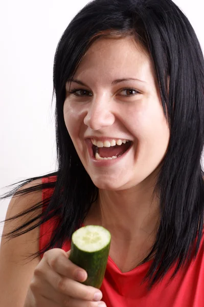 Uma jovem mulher comendo um pepino orgânico — Fotografia de Stock