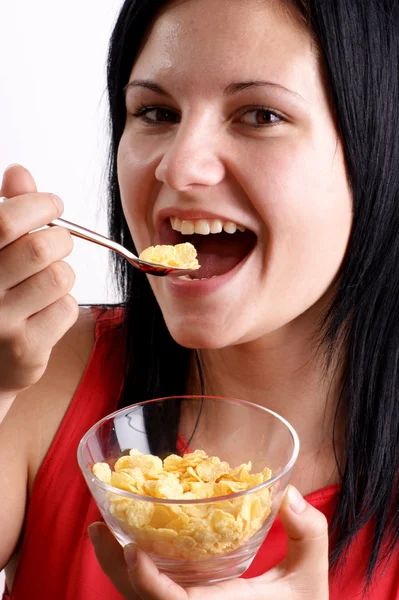 Une jeune femme mangeant des flocons de maïs dans un bol — Photo