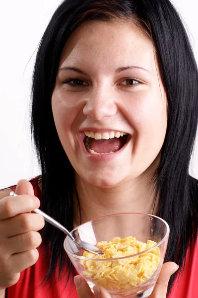 Una joven comiendo copos de maíz de un tazón — Foto de Stock