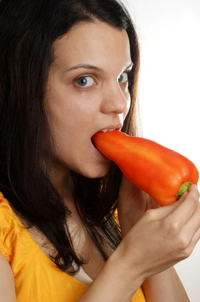 Une jeune femme mange un paprika rouge — Photo