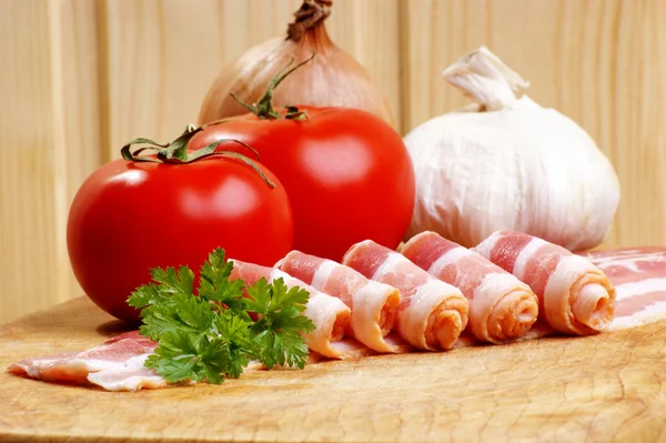 Bacon, tomate orgânico e alho em um prato de madeira — Fotografia de Stock