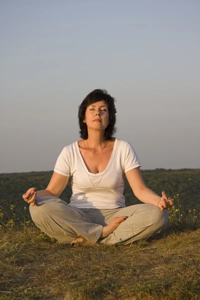 Frau beschäftigt sich mit Yoga bei Sonnenuntergang. — Stockfoto