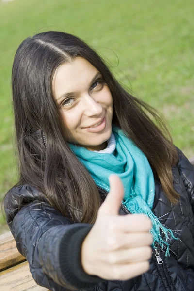 Krásná dívka v parku s úsměvem. palec — Stock fotografie