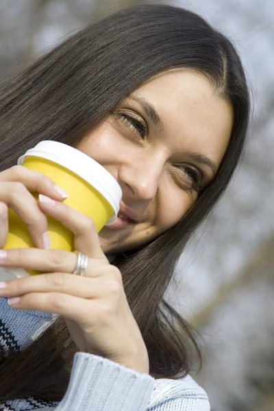 Mooi meisje in een park drinken koffie — Stockfoto