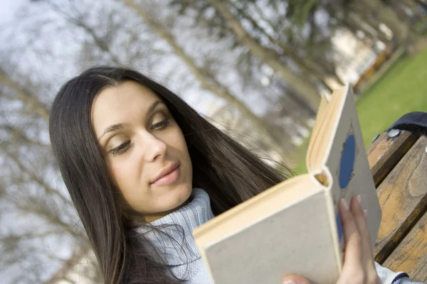 Jonge vrouw in een park lezing — Stockfoto